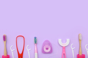 Toothbrushes with floss toothpicks and tongue scraper on lilac background