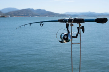 Fish rod mounted on a spring rod holder with blurred background of water and landscape on horizon