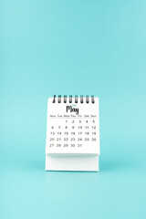 May 2024 white desk calendar on blue background.