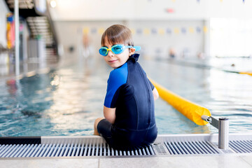 Cute preschool child, boy, swimming in swimming pool, wearing wetsuit - 796284937