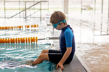 Cute preschool child, boy, swimming in swimming pool, wearing wetsuit - 796284948