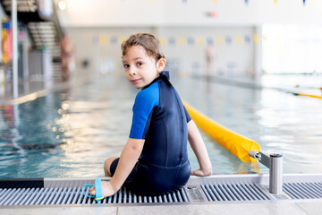 Cute preschool child, boy, swimming in swimming pool, wearing wetsuit - 796284964