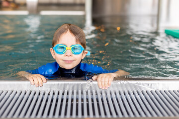 Cute preschool child, boy, swimming in swimming pool, wearing wetsuit - 796284975