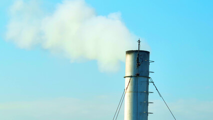 Against the canvas of a flawless blue sky, the industrial plant exhales plumes of ghostly white...