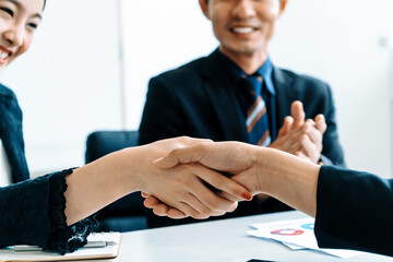 Business people agreement concept. Businessman and Asian businesswoman do handshake in the office....