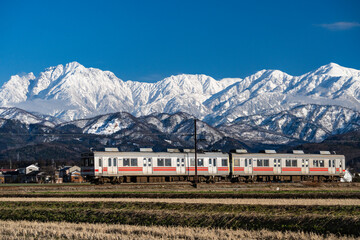 剱岳を眺めながら走る富山地方鉄道の電車