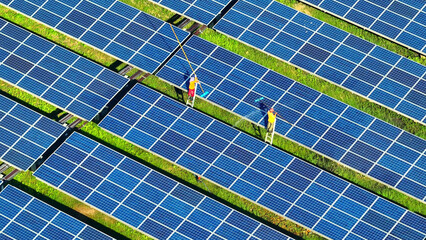 As the sun's rays beat down, workers scrub away dust and grime from solar panels, revealing their...