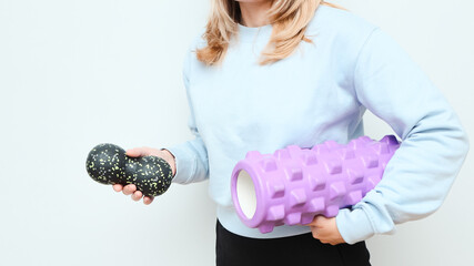 Woman holding massage rollers for myofascial release in her hands. Fitness trainer with items for myofascial release.