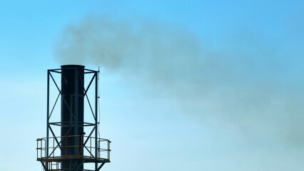 An industrial plant billows thick, black smoke into the azure sky, symbolizing environmental...