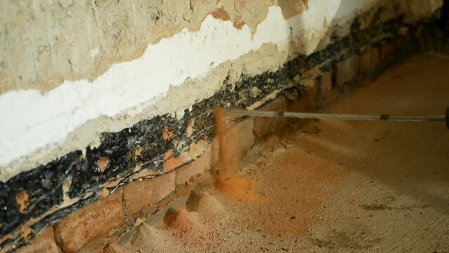Injection drilling fluid house hole wall masonry drill close-up into porous inject undercutting cut and insulating building against moisture. work of waterproofing and cutting into brick, detail work