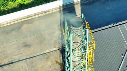 The industrial plant exhales smoky tendrils, a somber dance of pollution, staining the heavens with...