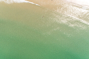directly above aerial drone view of two people in turquoise water on the shore of a beach enjoying...