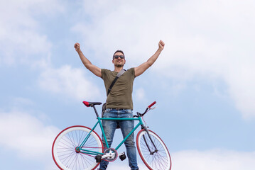 Man triumphantly raises arms with bike