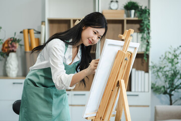 Concentrated woman in front of easel painting at home studio.
