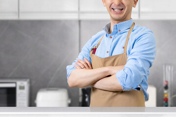 腕組みをしてキッチンに立つ笑顔の男性・料理イメージ