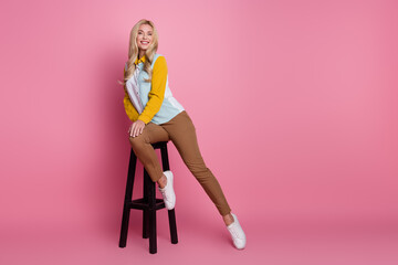 Fototapeta na wymiar Full length photo of positive pretty cute woman sitting stool in bar enjoying rest empty space isolated on pink color background