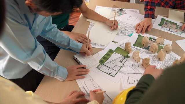 Architect and safety engineer discussion about building construction use blueprint on table with architectural document, measurement tool and wooden block scatter around at modern office. Delineation.