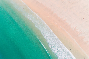 People enjoying summer.aerial drone view of the waves arriving at the shore of a beach. Foam and...