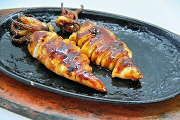 Grilled squids or 'Cumi Bakar' is a sweet and tangy seafood dish that is often sold as street food in Indonesia. It is marinated in sweet soy sauce and a mixture of spices before being grilled. 