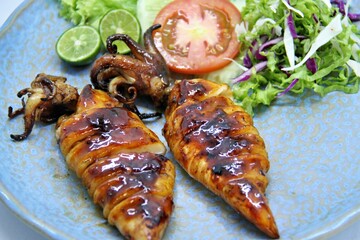 Grilled squids or 'Cumi Bakar' is a sweet and tangy seafood dish that is often sold as street food in Indonesia. It is marinated in sweet soy sauce and a mixture of spices before being grilled. 