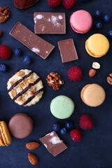 Macarons, chocolate, cookies, berries and various nuts on dark blue background. Top view.