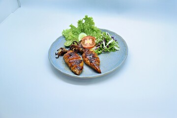 Grilled squids or 'Cumi Bakar' is a sweet and tangy seafood dish that is often sold as street food in Indonesia. It is marinated in sweet soy sauce and a mixture of spices before being grilled. 