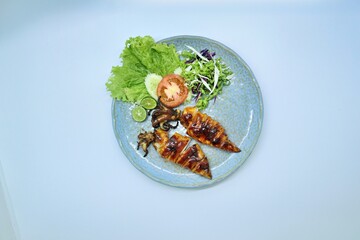 Grilled squids or 'Cumi Bakar' is a sweet and tangy seafood dish that is often sold as street food in Indonesia. It is marinated in sweet soy sauce and a mixture of spices before being grilled. 