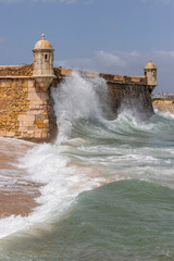 Fortress of Ponta da Bandeira gets hit by a huge wave in Lagos, Algarve, Portugal