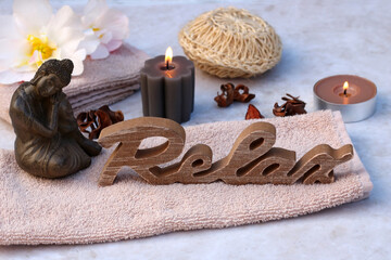 Spa arrangement with Buddha figure, candles and the word Relax.