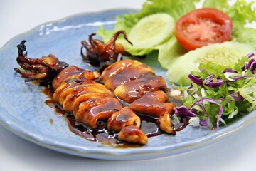 Grilled squids or 'Cumi Bakar' is a sweet and tangy seafood dish that is often sold as street food in Indonesia. It is marinated in sweet soy sauce and a mixture of spices before being grilled. 