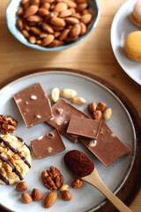 Cup of tea or coffee, cookies, macaroons, chocolate, various nuts and cocoa powder on wooden table. Selective focus.