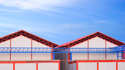 Two industrial cold storage warehouse buildings structure with white sandwich panel wall and electrical cable ladder against blue sky in factory construction site area