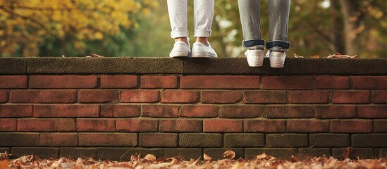Young girl with foot on brick wall in park