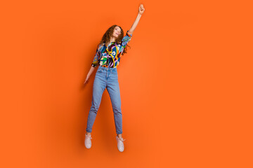 Photo of positive funny nice girl wear stylish print clothes arm hold placard empty space isolated on orange color background