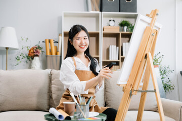 Asian Female painter do artwork in art workshop, painting supplies, oil pastels, two canvas easel,...