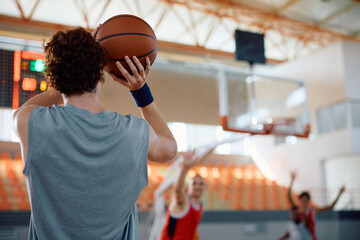 Rear view of basketball player shooting at hoop.