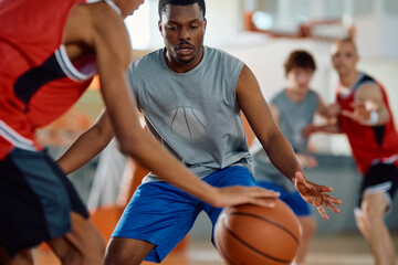 Defense player trying to block his opponent during basketball match on  court.