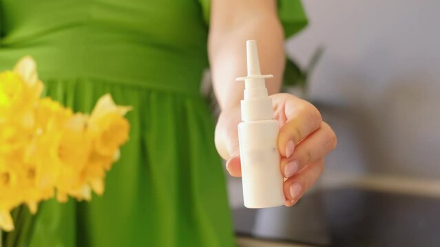 Close-up of hands with allergy spray, flowers in background, effective treatment for pollen allergy, antiallergic medication intake.
