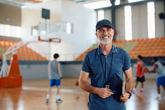 Happy basketball coach on court looking at camera.