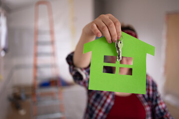 Woman holding paper house symbol and keys in front of camera, concept of life in new home. High quality photo