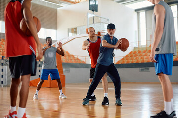 Basketball players practicing playing tactics with their coach during sports training