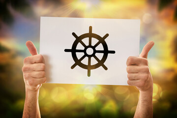 Hands okay holding a poster with dharma wheel in nature