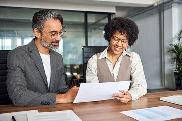 Two happy busy diverse business man and woman working at meeting, financial advisor manager showing paper document to customer consulting client about bank services, giving legal advice in office.