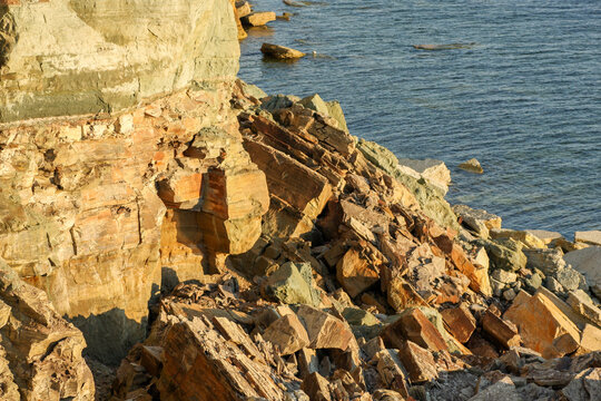 Pakri Cliff in Estonia with coastal erosion and collapsed cliff fragments by the sea in warm light