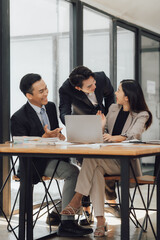 Group of businesspeople are sitting around a table in a business setting. They are all smiling and seem to be enjoying each other's company