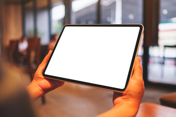 Mockup image of a woman holding digital tablet with blank white desktop screen in cafe - 796411585