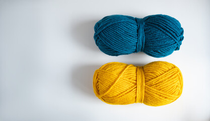 two balls of yellow blue thread for knitting or crocheting on a light background