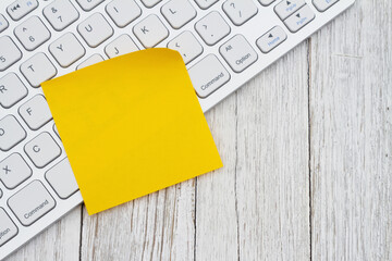 Computer keyboard with a yellow sticky note
