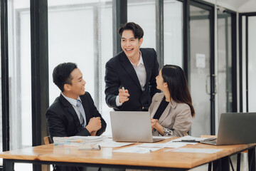 Young motivated Asian business team discussing oh business strategy in the modern meeting room.