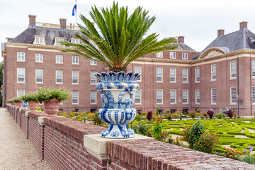 Delft blue flower pot with fern on a wall along one of the gardens of Paleis Het Loo in Apeldoorn,...